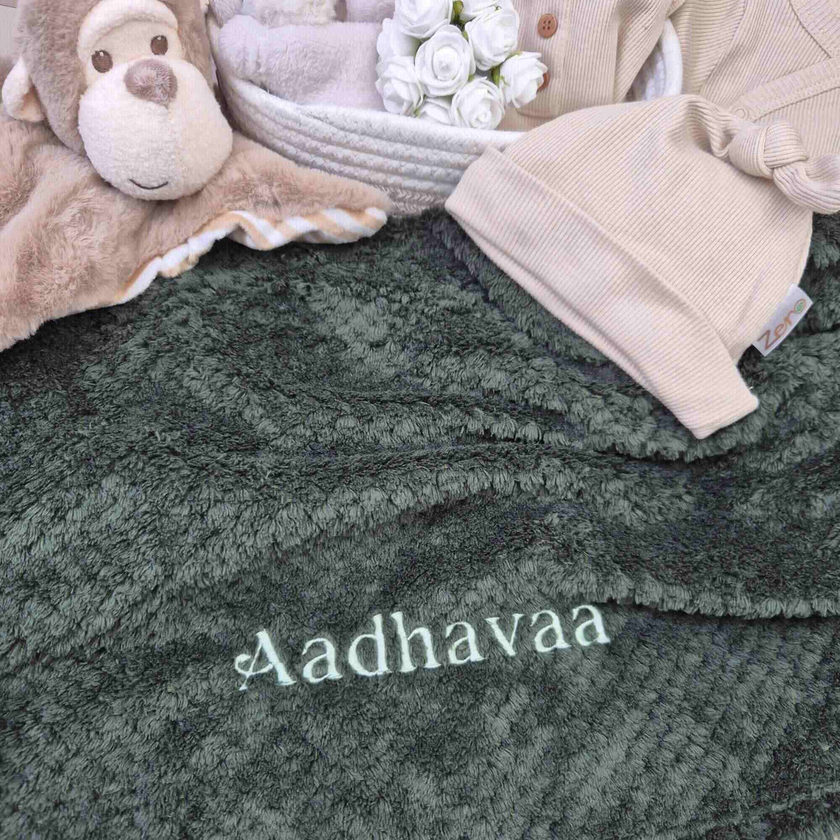 Personalised baby blanket in dark green waffle with embroidered name.