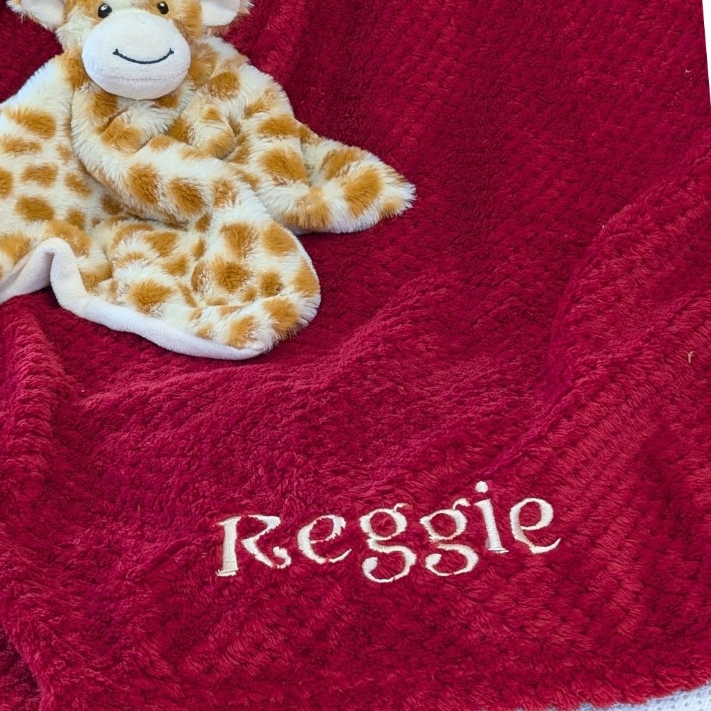 Burgundy red waffle baby blanket embroidered with the name Reggie