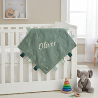 Persoanlised baby comforter in sage green with taggie ribbons and embossed dinosaurs pattern. 