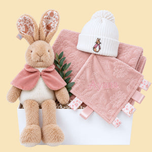 Luxury baby girl hamper with Beatrix Potter Flopsy Bunny soft toy, dusty pink floral blanket, white knitted bunny hat and personalised pink taggie comforter.