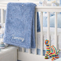 A personalised dark blue baby blanket with an embossed dinosaur theme.