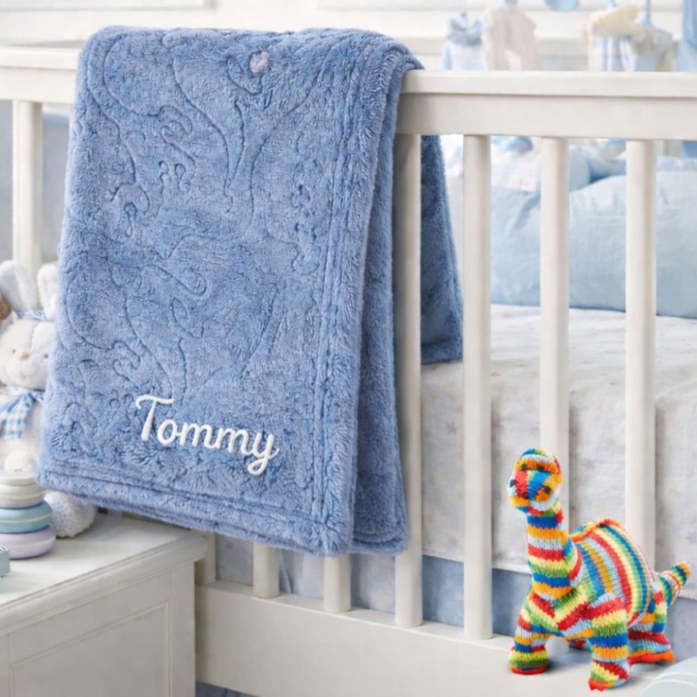 A personalised dark blue baby blanket with an embossed dinosaur theme.