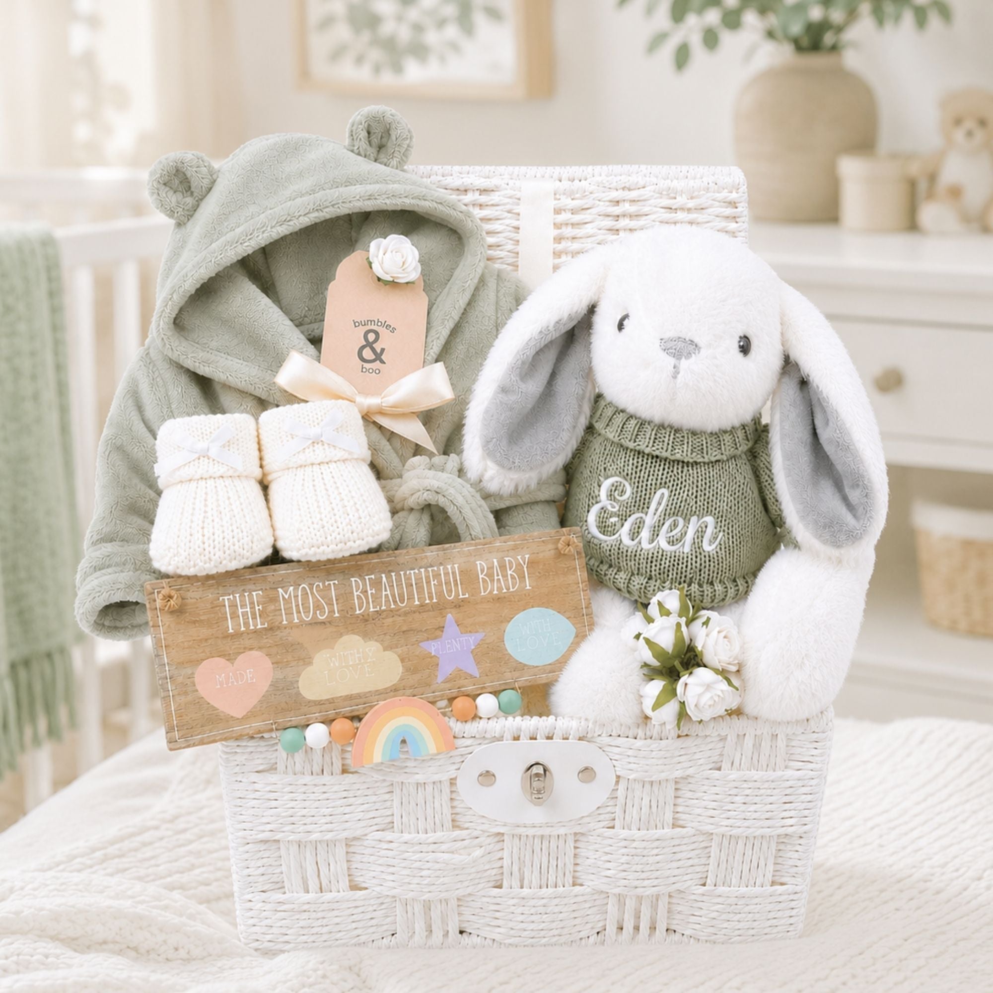 White new baby gifts hamper full of new baby gifts including bunny, booties and baby dressing gown.