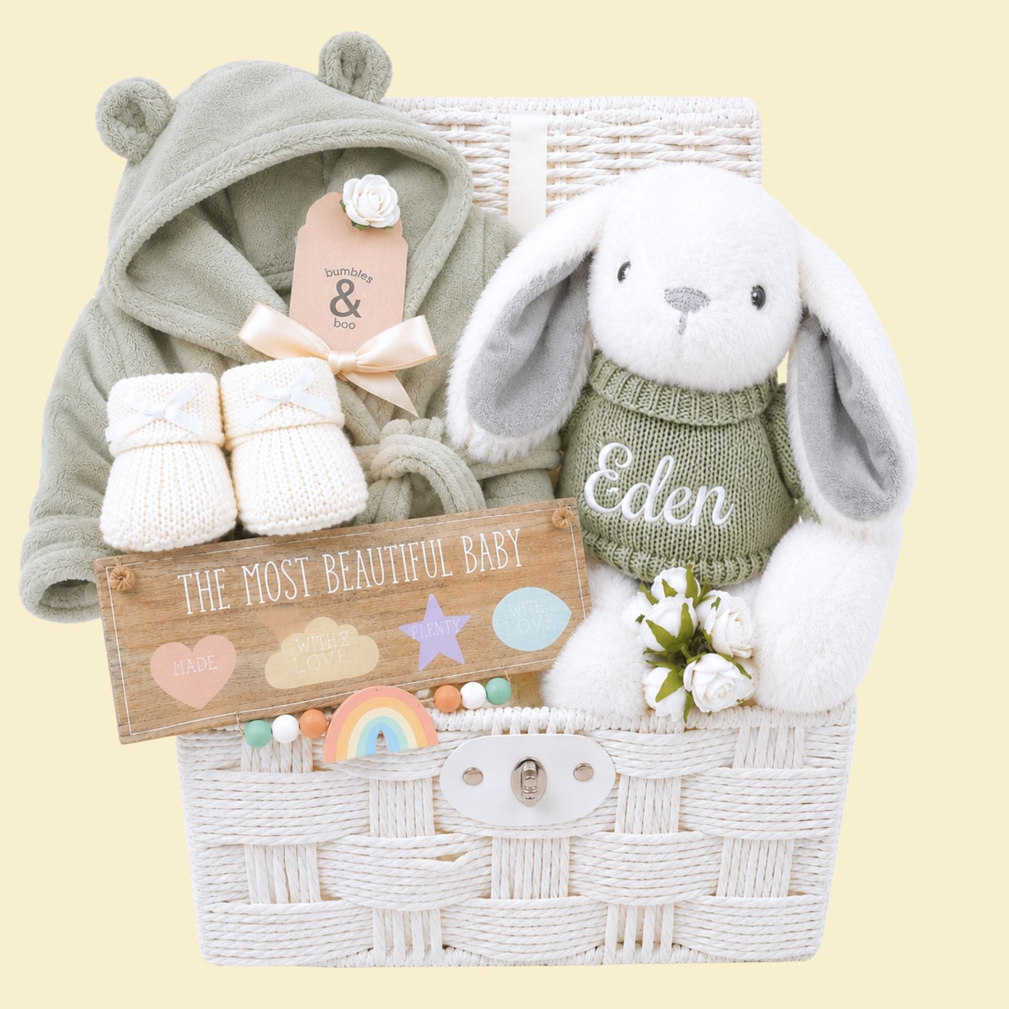 White new baby gifts hamper full of new baby gifts including bunny, booties and baby dressing gown.
