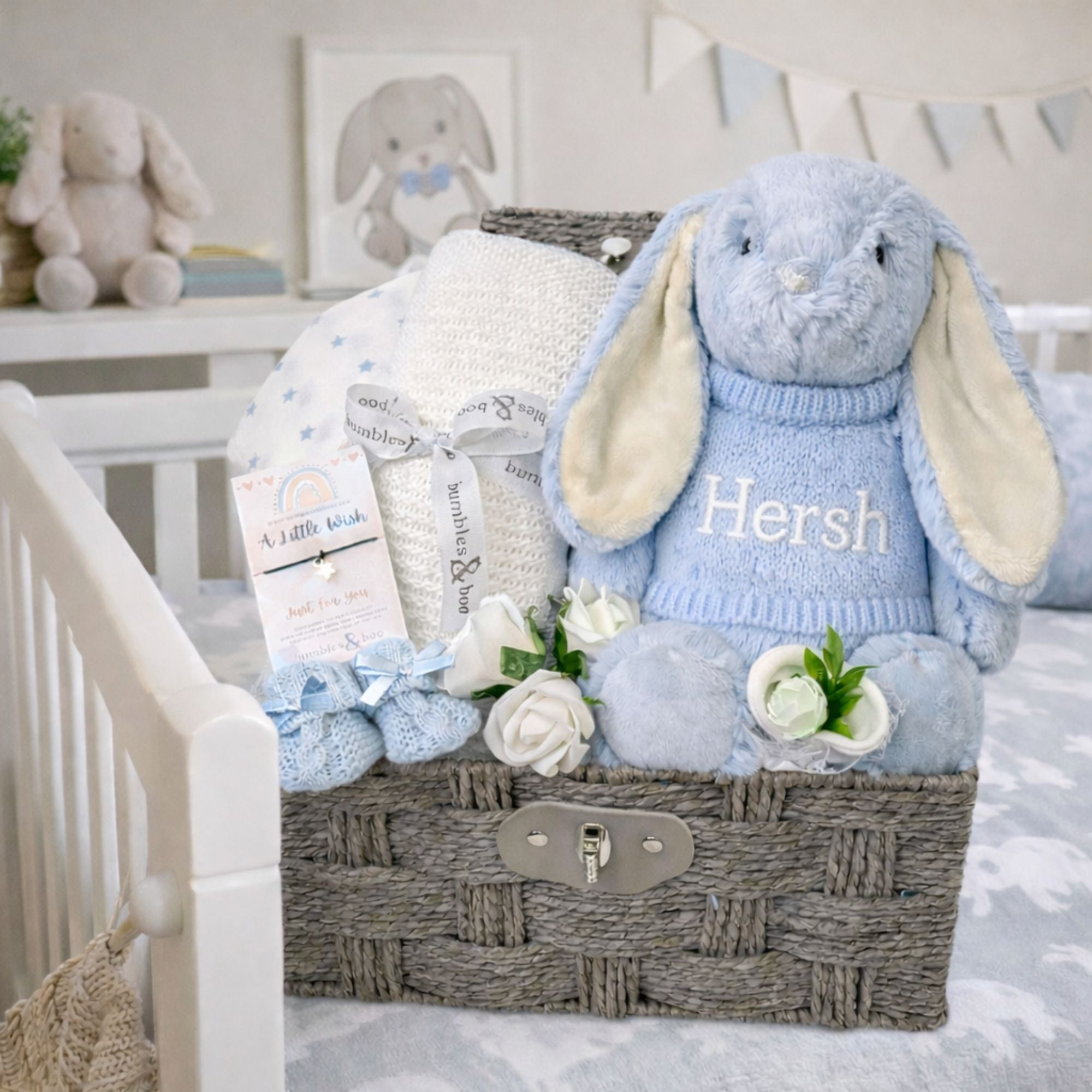 Baby gift basket with personalised plush bunny toy, blanket, and socks in a nursery basket.