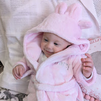 Baby wearing a pink dressing gown with an ear-detail hood and an embroidered name.