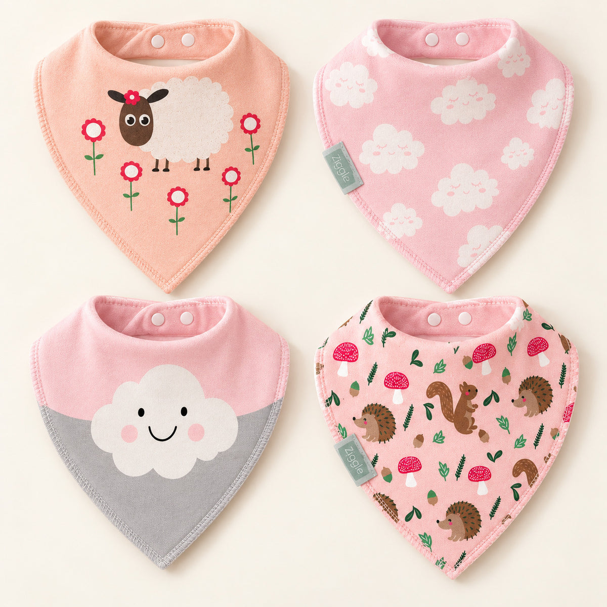 Four pink bandana bibs laid flat with sheep, white clouds, a smiling cloud and woodland animal designs.