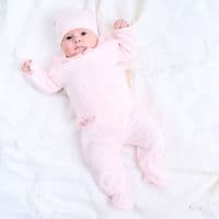 Full-length view of a baby lying down in the pink three piece knitted outfit.