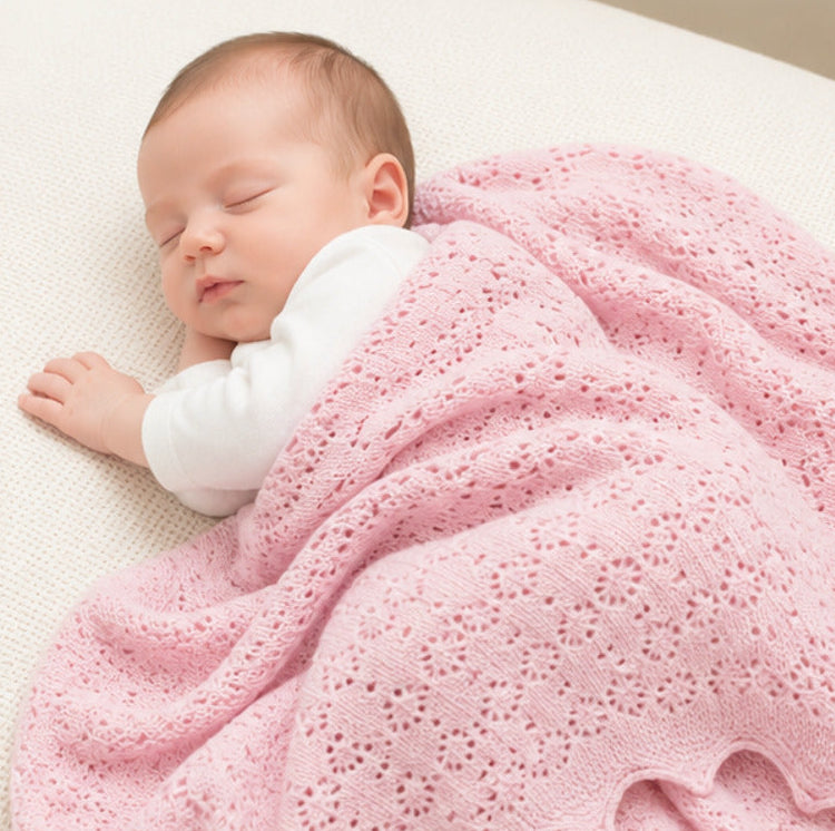 Pink cashmere baby blanket. This shawl has a delicate pointelle openwork pattern and is covering a sleeping newborn baby