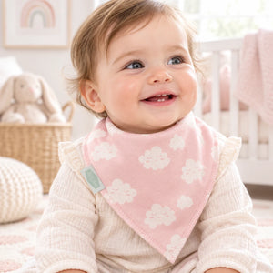 Baby wearing a pink bandana dribble bib patterned with small white clouds.