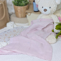 A pink 100% cotton muslin wrap for a baby.