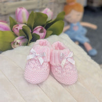 Pink knitted baby booties with little pink bows.