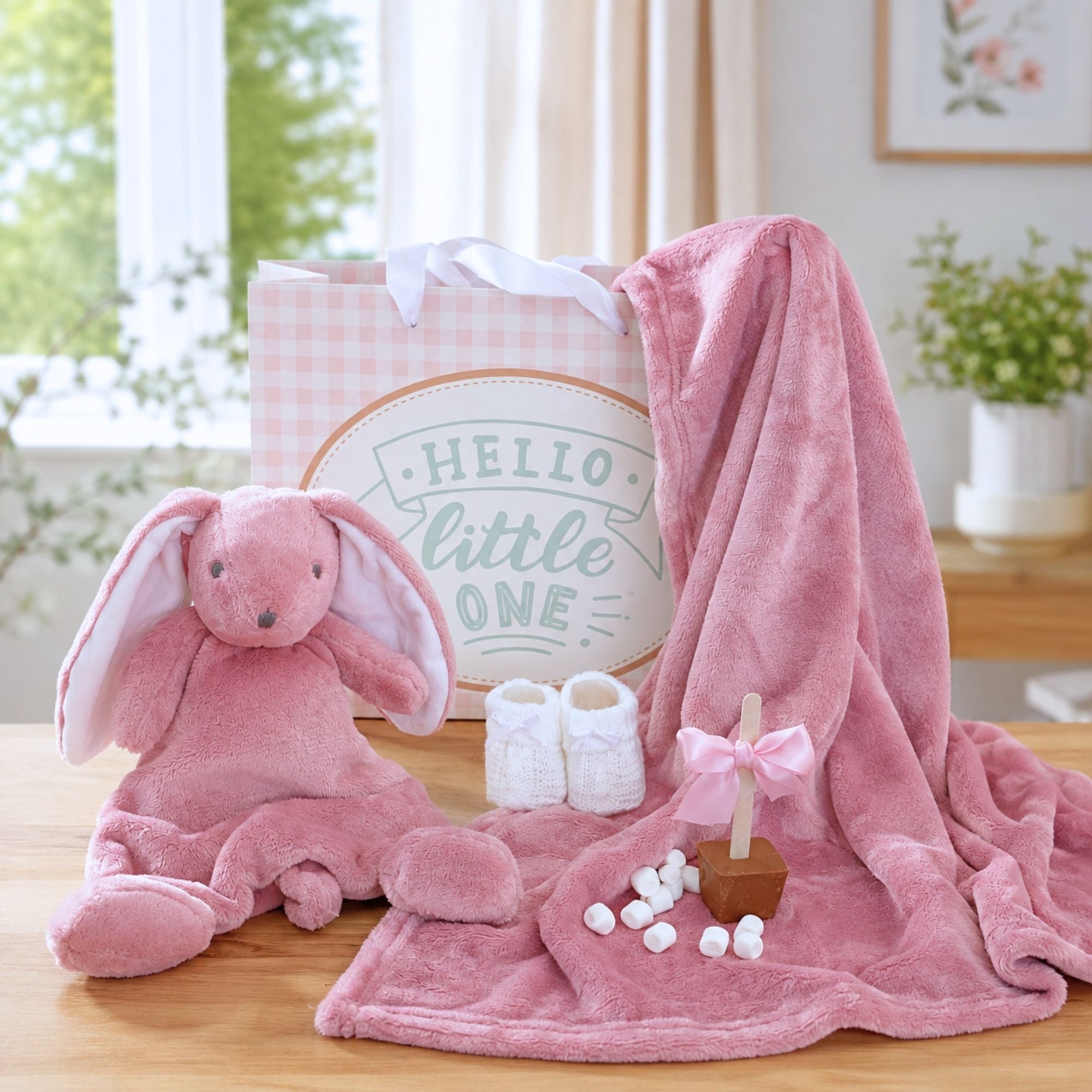 A pink baby girl gifts set, featuring a plush pink bunny toy and a soft pink blanket