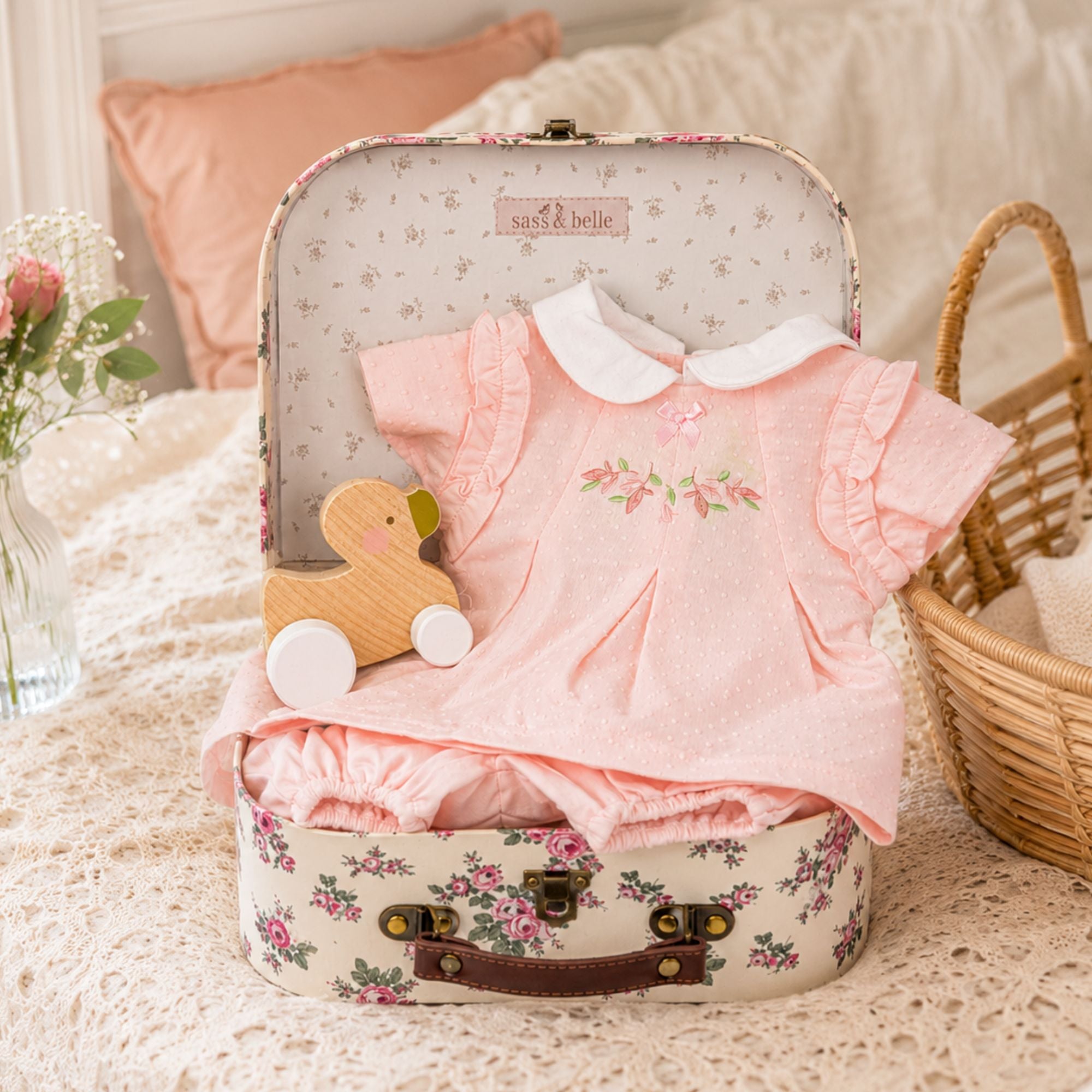 Baby girl gifts hamper with floral baby clothing and a wooden push along duck