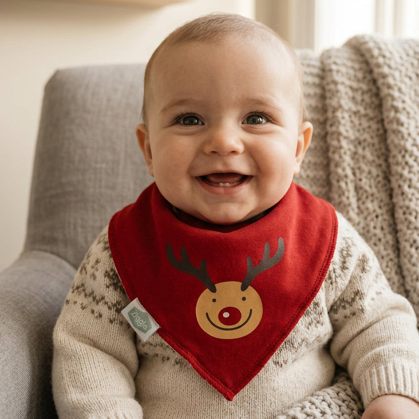 Baby wearing a red bandana bib with a smiling reindeer face and antler design.