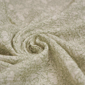 Close-up of sage green baby muslin fabric with an intricate leafy pattern.