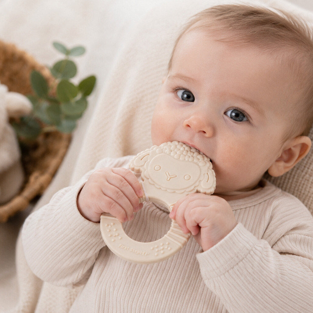 Baby teether in the shape of a lamb, with a baby holding the ring shaped grip. Made from food-grade silicone
