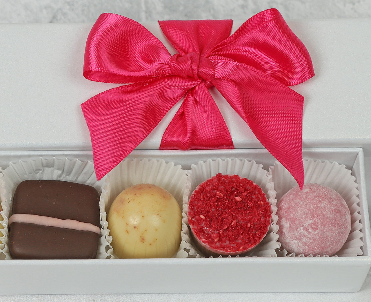 White gift box with pink ribbon and luxury chocolates