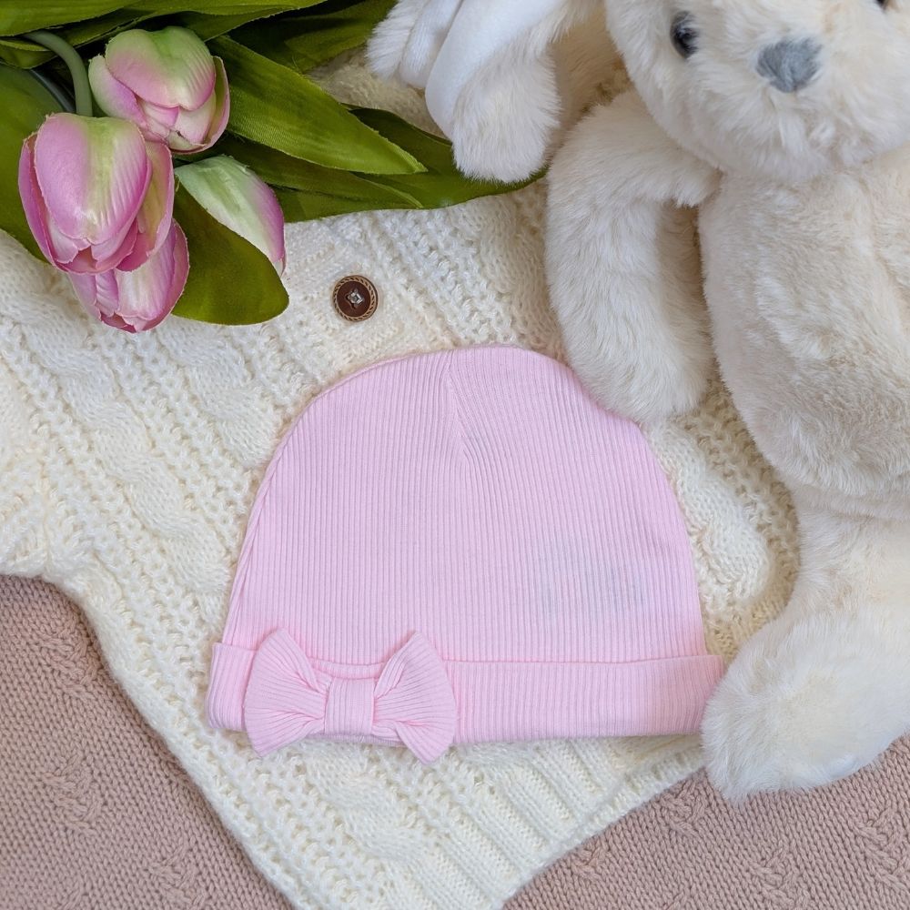A pink beanie hat for a baby girl with a bow
