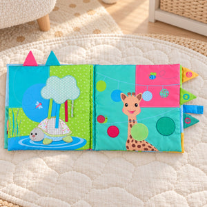 Sophie la Girafe Sensitive Book open to turtle and giraffe activity pages on a quilted nursery playmat