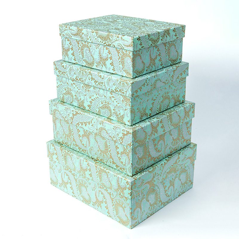 Stack of 4 different sized teal gift boxes with golden paisley patterning