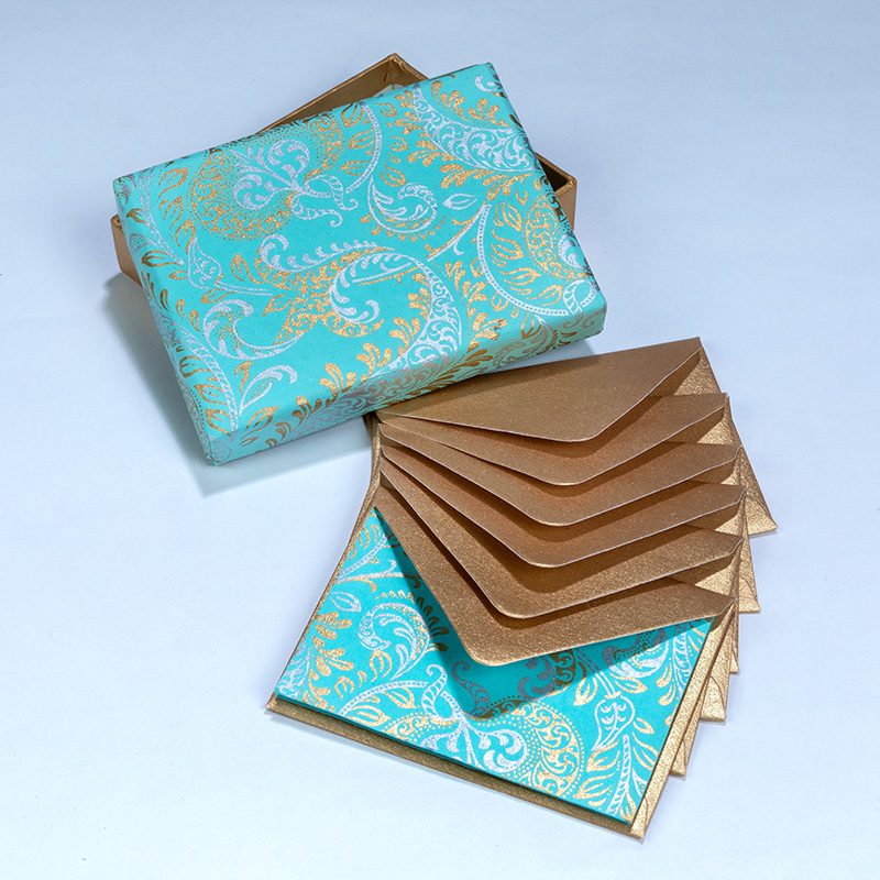 Teal box with gold paisley patterning. Contains similar patterned cards with golden envelopes