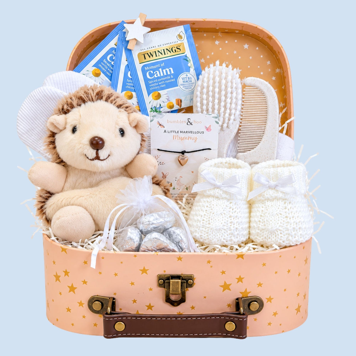 Affordable baby gift hamper with chocolates, tea, soft toy, baby mittens, brush set, and keepsake trunk.