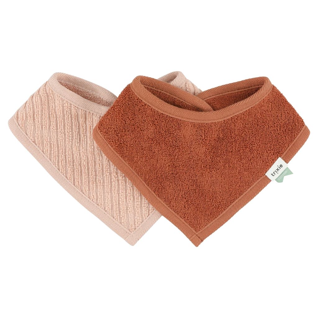 Trixie Hush Rose bandana bib pair with a rust terry bib in front of a pale pink striped bib.