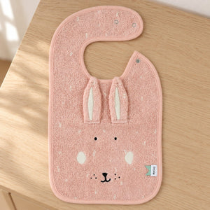 Pink Mrs Rabbit bib with long fabric ears and a rabbit face laid flat on a sunlit wooden dresser.
