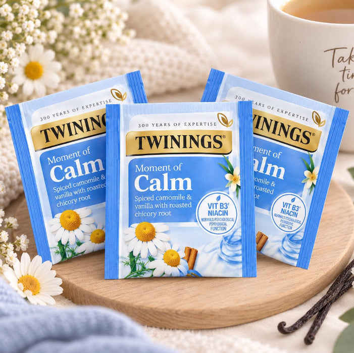 Twinings Moment of Calm tea sachets arranged on a wooden tray beside a mug.