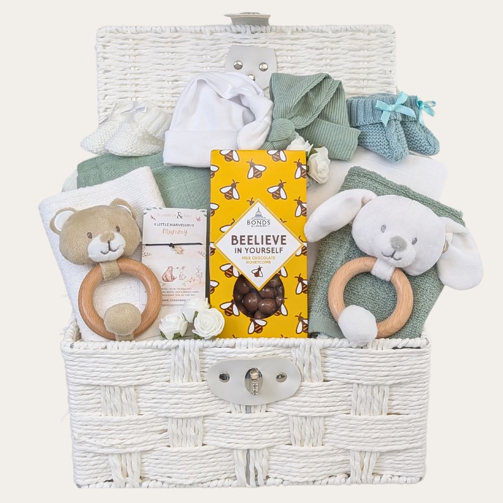 A twin baby gift basket with toys and items in a white hamper