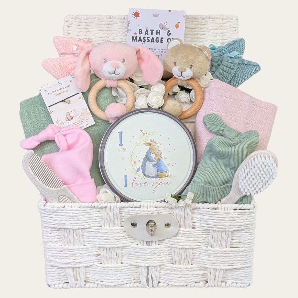 A gift for twin babies in a hamper basket with pink & sage green baby products for twins by Bumbles and Boo.