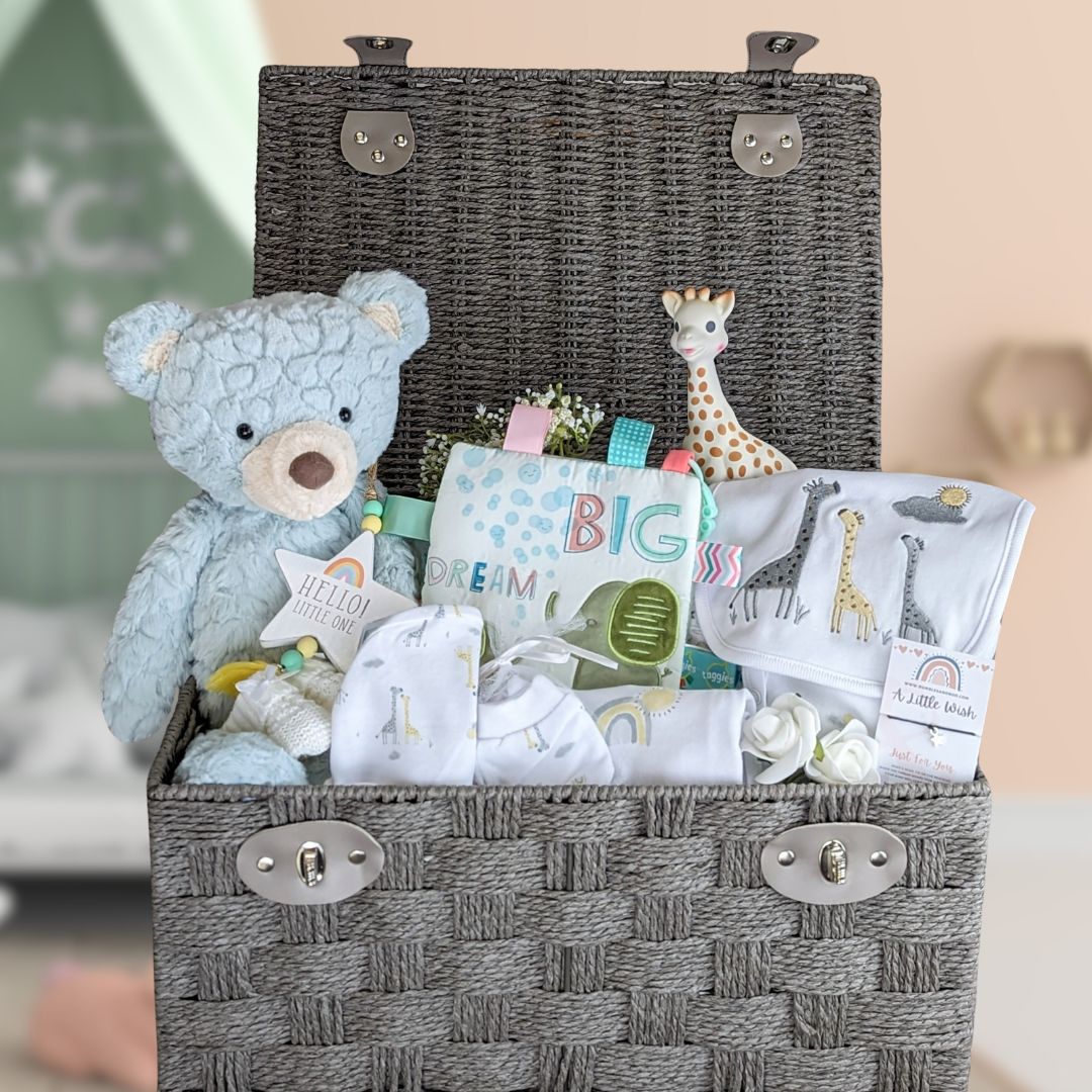 large baby hamper with clothing and teddy bear.