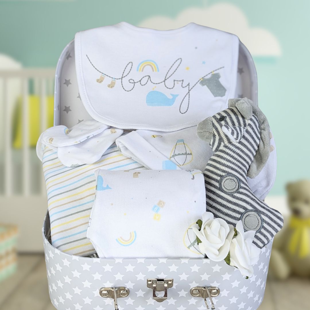 new baby hamper trunk with cotton clothing set and giraffe baby rattle. Presented in a keepsake luggage trunk hamper