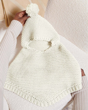 White knitted baby poncho showing hood and pom-pom detail