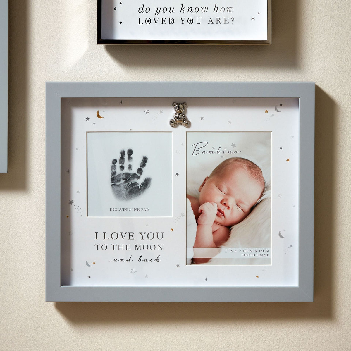 White handprint photo frame displayed on a wall with teddy bear detail.