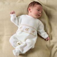 Full-length view of a baby lying on a taupe blanket in the white footed rocking horse onesie.