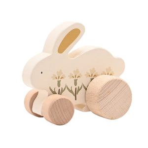 Angled view of a cream wooden bunny showing floral decoration and four natural wood wheels.