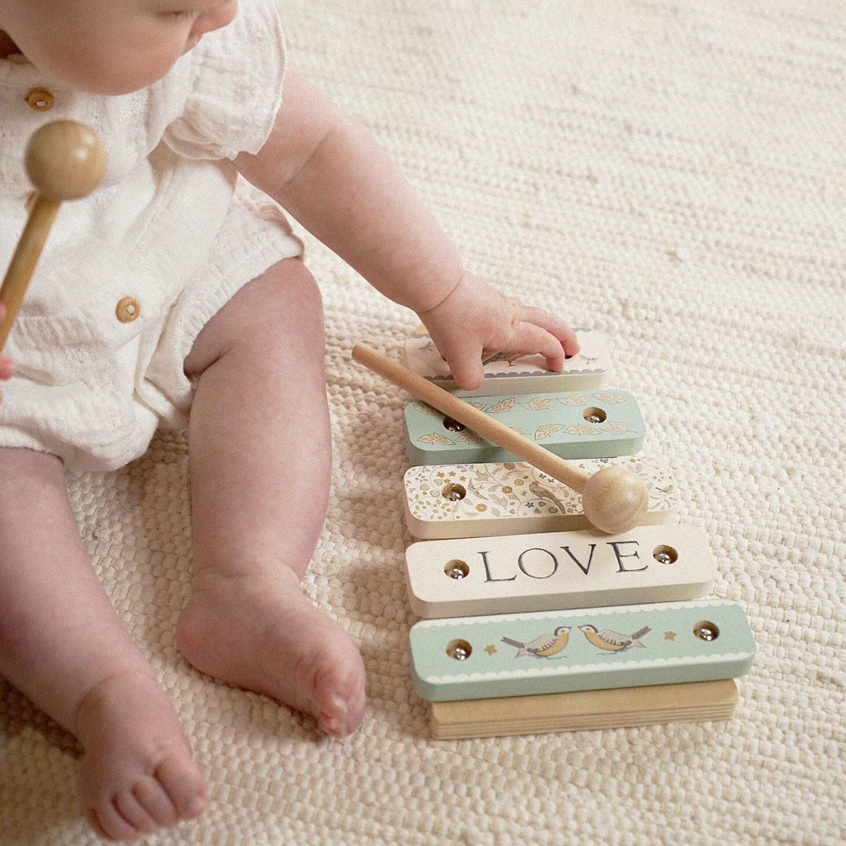Child beside the wooden xylophone with a mallet lying across the decorated bars