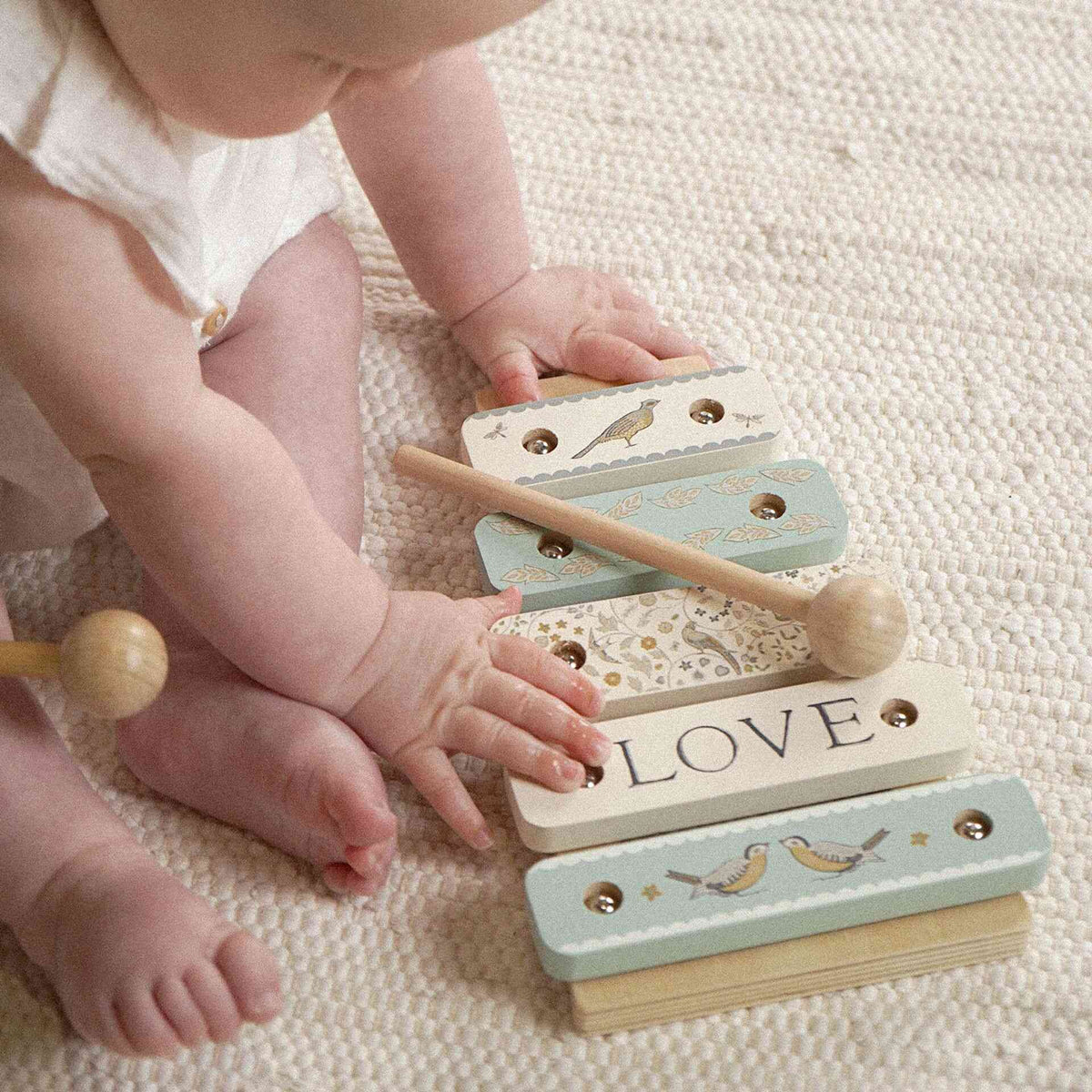 Child reaching toward LOVE bar on the patterned wooden toy xylophone