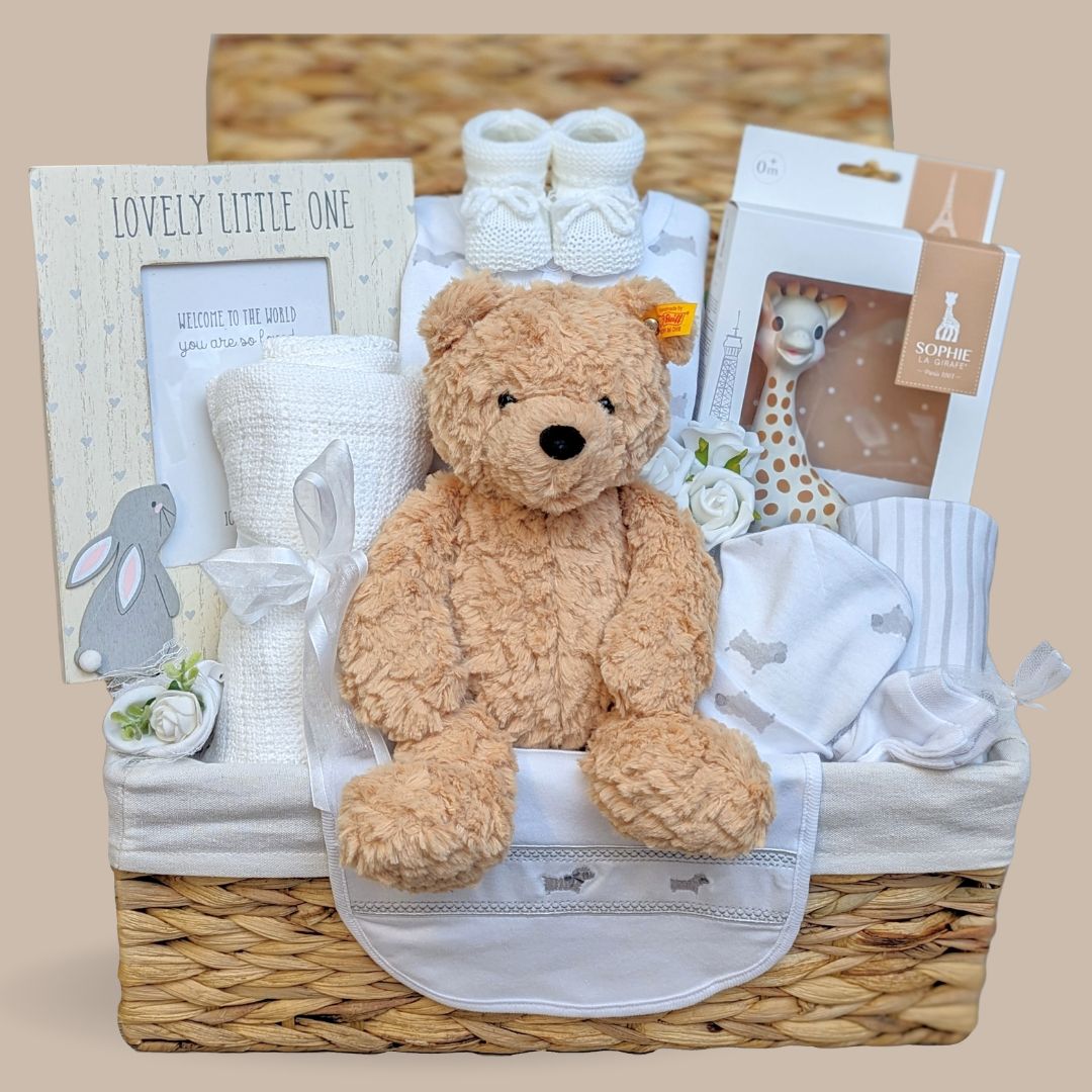 New baby hamper filled with beautiful and practical delights. Presented in an eco-friendly basket. Sophie La Giraffe, Steiff Teddy, Clothing Set, Photo Frame, Baby Booties and Blanket.