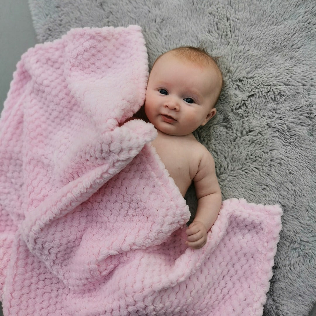 Baby with pink waffle baby blanket.