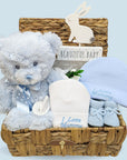 Gifts for  a baby boy in a hamper basket. With blue teddy bear, baby hats, baby booties and nursery plaque. 
