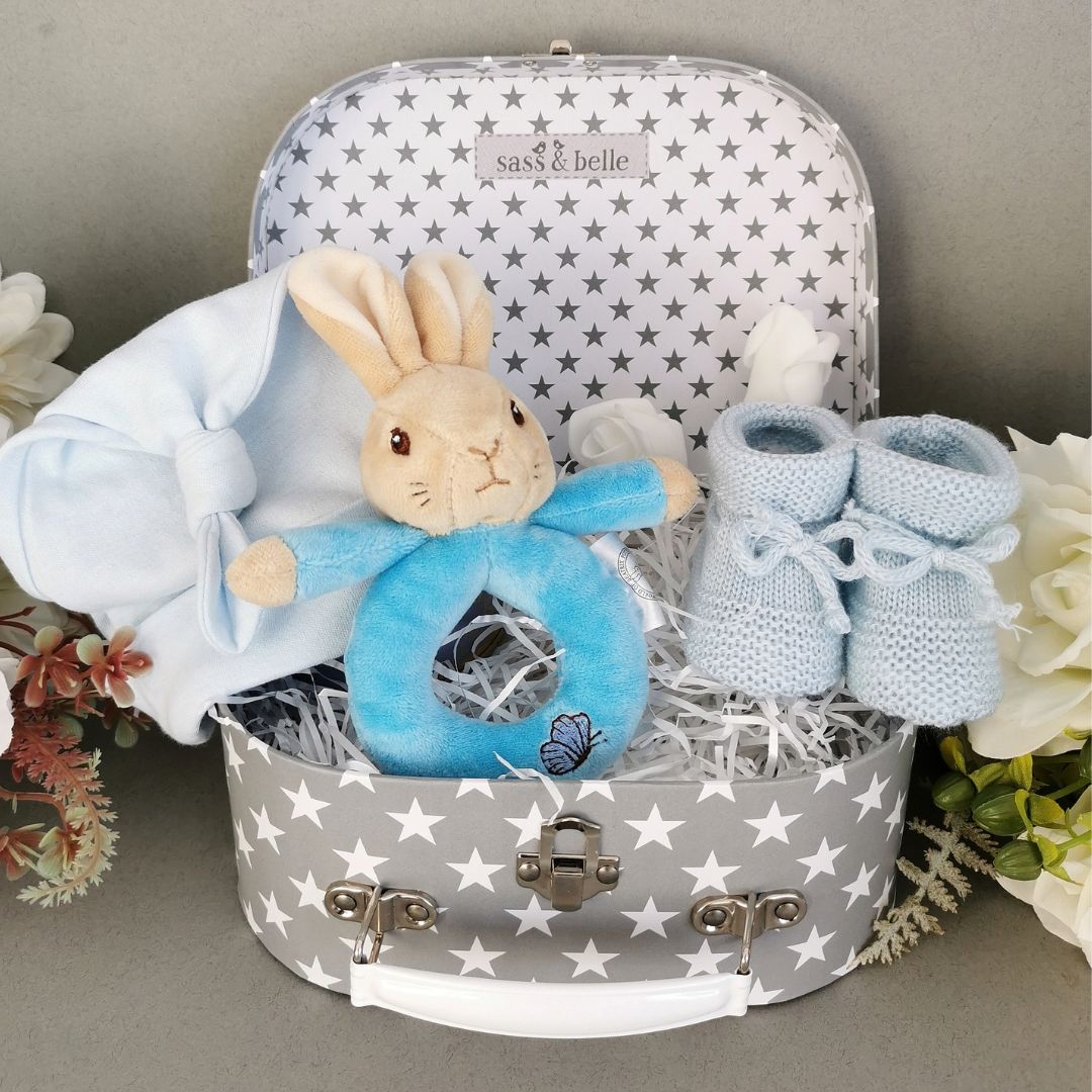 Baby boy keepsake hamper trunk with peter rabbit bean rattle, blue baby hat and baby booties.