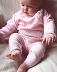 Baby wearing a pink knitted outfit.