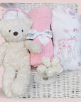 Baby girl hamper with white teddy, pink blanket and white babygrow with a deer design.