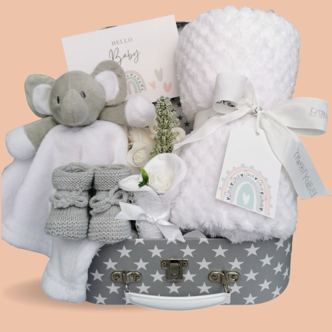 New baby gift hamper with white blanket and elephant comforter in a grey hamper with white stars.