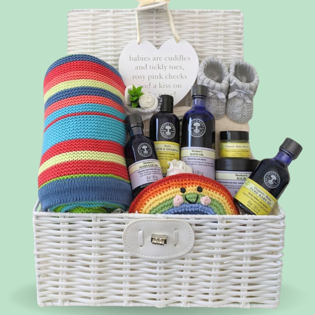 Baby shower hamper basket with gifts including a bright stripy blanket and Neal's Yard organic skincare.