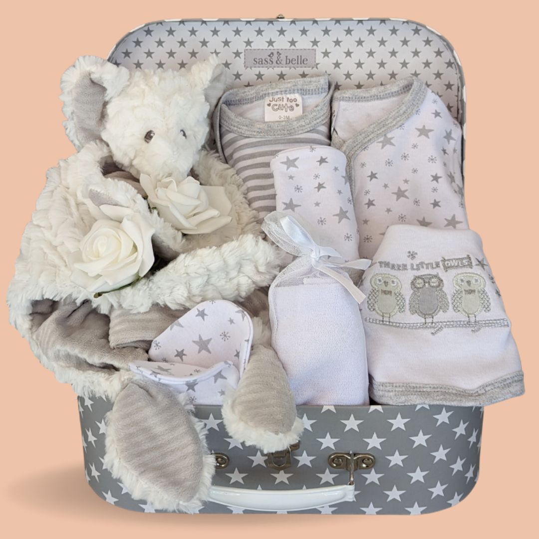 Baby shower hamper with gifts including baby clothes in white with grey stars and white elephant comforter in a grey hamper.