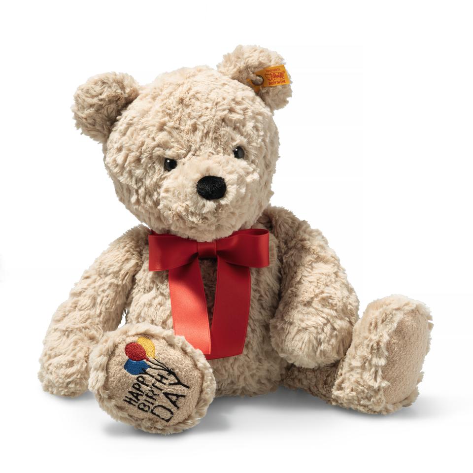 A beige soft teddy bear by toy maker Steiff with happy birthday embroidered on the foot